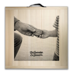 Framed sepia photo of an adult handing a round coin-like token to a child, symbolizing generations passing on values.