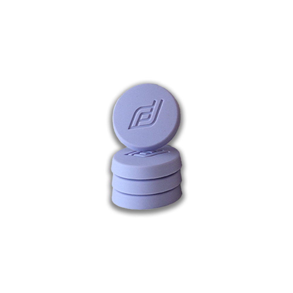 Lavender circular silicone cap with an embossed logo, stacked atop similar caps